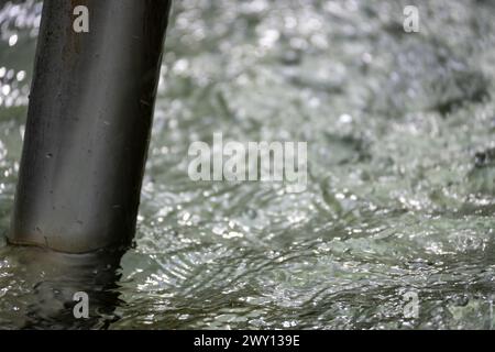 ravvicinare l'acqua che scorre da una fontana sotto la pioggia Foto Stock