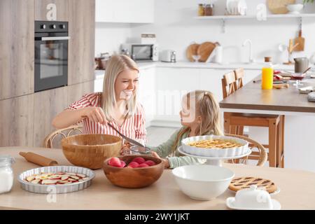 Madre felice con la sua piccola figlia che cucina la torta di mele in cucina Foto Stock