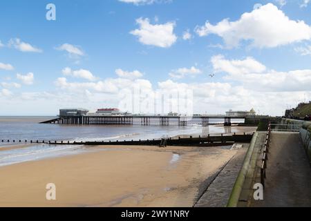 Molo Cromer, Norfolk. Cromer Pier in una giornata di sole con qualche nuvola bianca. Un'immagine a colori della parte inferiore del molo. La marea sta per uscire. Foto Stock