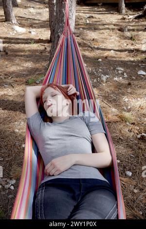 adolescente che dorme su un'amaca nella foresta con la mano dietro la testa. Foto Stock