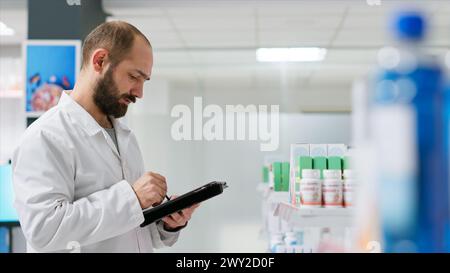 Il lavoratore medico che conta le scatole dei medicamenti collocate sugli scaffali, lavorando sull'inventario della farmacia per garantire il pieno stock per i clienti. Farmacista che svolge attività logistica con pacchetti di pillole. Foto Stock