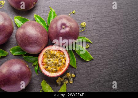 Frutti della passione viola scuro e metà del frutto della maracuya isolati su sfondo grigio grafite ardesia. Foto Stock