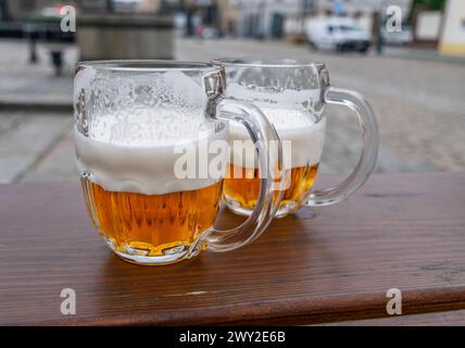 Tazze da birra o bicchieri da birra sul tavolo in legno della città sullo sfondo. Foto Stock
