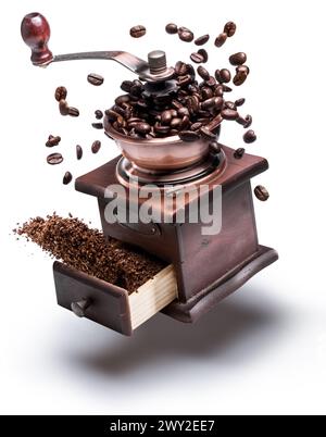 Immagine concettuale del macinacaffè manuale o del macinacaffè e dei chicchi di caffè che levitano nell'aria intorno ad esso. Foto Stock