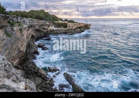 Il sole sorge lentamente sulle scogliere frastagliate, incontrando le acque turchesi dell'Oceano Pacifico lungo il Mahaulepu Heritage Trail a Koloa, Hawaii Foto Stock