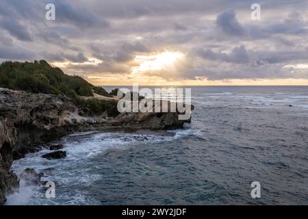 Il sole sorge lentamente sulle scogliere frastagliate, incontrando le acque turchesi dell'Oceano Pacifico lungo il Mahaulepu Heritage Trail a Koloa, Hawaii Foto Stock