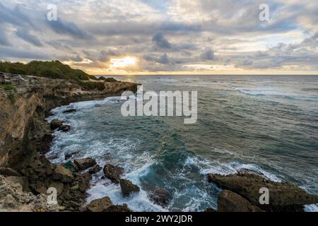 Il sole sorge lentamente sulle scogliere frastagliate, incontrando le acque turchesi dell'Oceano Pacifico lungo il Mahaulepu Heritage Trail a Koloa, Hawaii Foto Stock