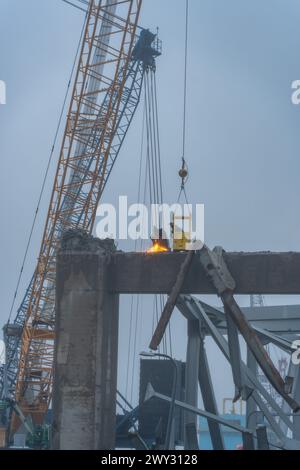 Il personale altamente addestrato delle operazioni di salvataggio usa una torcia esotermica per tagliare una parte del crollo del Francis Scott Key Bridge, 2 aprile 2024 a Baltimora, Maryland. Una volta separati dalla struttura, le sezioni più piccole del ponte in acciaio verranno spostate in un sito di smaltimento. Gli sforzi fanno parte della missione più ampia per liberare il canale di Fort McHenry. Lo U.S. Army Corps of Engineers, Baltimore District, ha attivato il suo Emergency Operations Center, marzo 26, aprendo la strada a centinaia di specialisti in ingegneria, costruzioni e operazioni per fornire supporto all'età locale, statale e federale Foto Stock