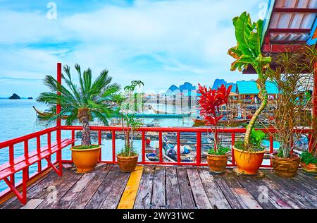 La vecchia terrazza in legno della palafitta, decorata con piante in vasi contro il porto con barche da pesca, il villaggio di Ko Panyi e l'Ao Phang Nga National Foto Stock