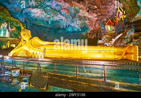 PHANG NGA, THAILANDIA - APRILE 28: Imponente statua del Buddha sdraiato, ricoperta d'oro, nella grotta Tham Yai del Tempio buddista della grotta Wat Suwan Kuha, ON Foto Stock