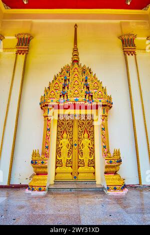 La porta a forma di guglia scolpita dell'Ubosot del Tempio di Wat Suwan Kuha e la porta, decorata con figure devata (divinità), Phang Nga, Thailandese Foto Stock