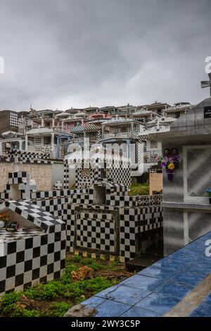 Famoso cimitero, molti mausolei o grandi tombe decorate con piastrelle, spesso in bianco e nero. Edifici densamente costruiti sotto una spettacolare copertura nuvolosa Foto Stock