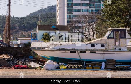 Grande imbarcazione in stato di abbandono nel bacino di carenaggio con edifici e alberi sullo sfondo in Corea del Sud Foto Stock