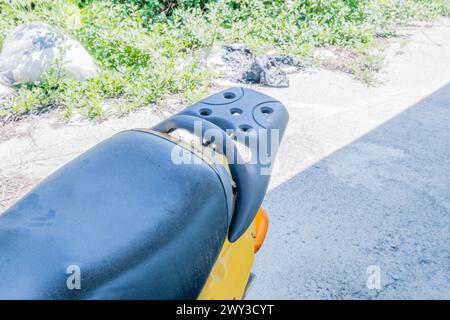 Sedile e schienale strappati di un piccolo scooter giallo con erba alta sullo sfondo nelle giornate di sole in Corea del Sud Foto Stock