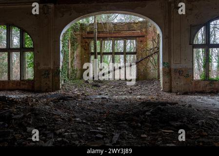 Vista interna di un edificio fatiscente con finestre ad arco e detriti sul pavimento, Beelitzheilstaetten, ex sanatorio polmonare, Beelitz Foto Stock