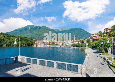 Bellissimo lago italiano tra le montagne. Lago di Mergozzo e città di Mergozzo, Italia. Passeggiata pedonale lungo il lago in estate con cielo azzurro Foto Stock