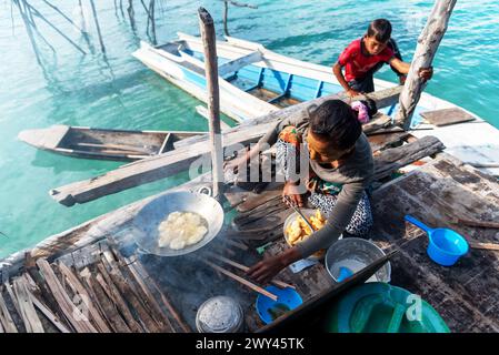 Semporna, Malesia - 20 novembre 2021: Bajau laut donna che cucina frittelle di banana Foto Stock