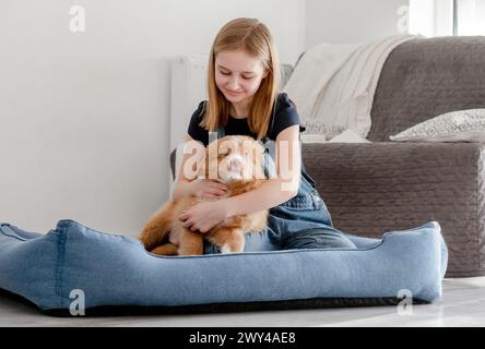 Piccola ragazza con cucciolo Toller siede nel Blue Dog Bed, Nova Scotia Duck Tolling Retriever Foto Stock