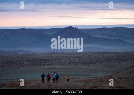 Un gruppo di atleti che corrono lungo un sentiero in una valle di montagna. All'inizio della primavera, tempo coperto, pittoresco paesaggio circostante. Sport all'aperto Foto Stock