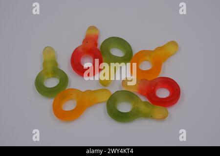 Caramelle colorate inusuali e non standard: Verde, giallo, rosso, giallo, arancione, sotto forma di chiave disposte su uno sfondo di plastica bianco. Foto Stock