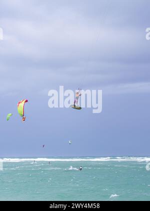 Kiteboarding. Divertimento nell'oceano. Sport estremo Kitesurf. Kitesurfer che salta in alto nell'aria che esegue le trick durante la sessione di kitesurf Foto Stock