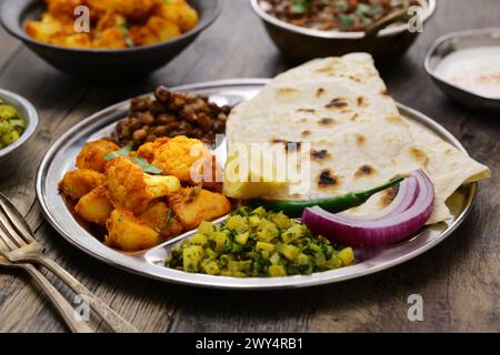 Piatto vegetariano in stile indiano. kala chana masala, aloo gobi ki sabzi, mooli ki sabzi e chapati. Foto Stock