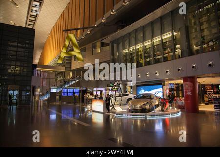 Terminal dell'Aeroporto Internazionale di Hamad con tutti i cancelli e i viaggiatori che passano. Foto Stock