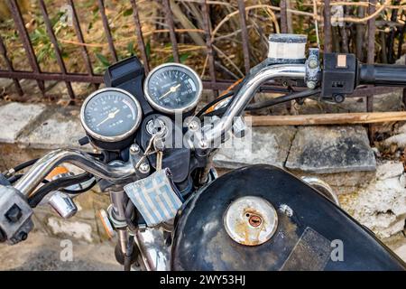 Primo piano del vecchio cruscotto della motocicletta arrugginito con portachiavi con bandiera nazionale greca Foto Stock