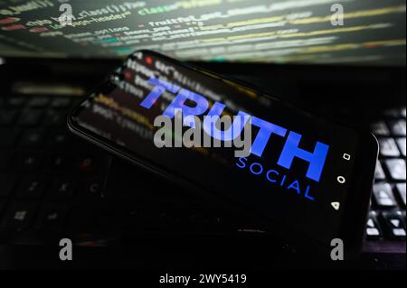 In questa immagine viene visualizzato un logo Truth Social su uno smartphone con codifica sullo sfondo. Foto Stock