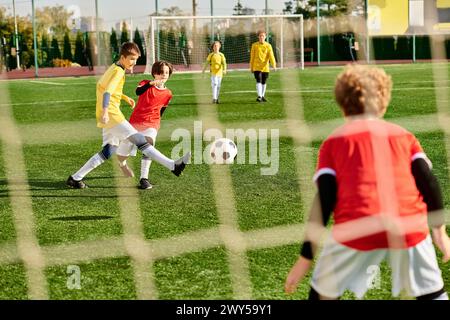 Un vivace gruppo di bambini che giocano a un appassionato gioco di calcio, corsa, calcio e passaggio della palla con pura gioia ed energia. Foto Stock