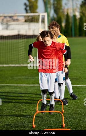 Un gruppo di giovani uomini esuberante si erge in cima a un campo da calcio, uniti per festeggiare e vincere dopo una partita combattuta. Le loro posizioni dinamiche conv Foto Stock