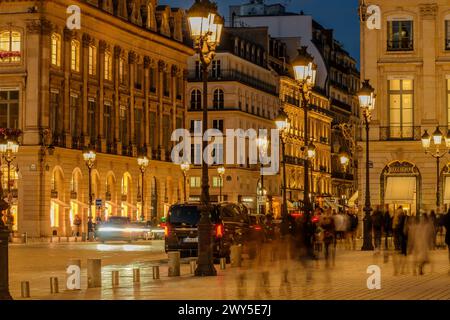 Parigi, Francia - 17 febbraio 2024: Vista dei lampioni illuminati nella trafficata Place Vendôme con i suoi negozi e hotel di lusso a Parigi in Francia Foto Stock