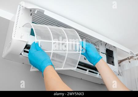 La persona sta pulendo il filtro dell'aria di un condizionatore d'aria Foto Stock