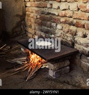 Pane piatto egiziano cucinato su fornelli a vista nella zona cucina all'aperto di un contadino Foto Stock