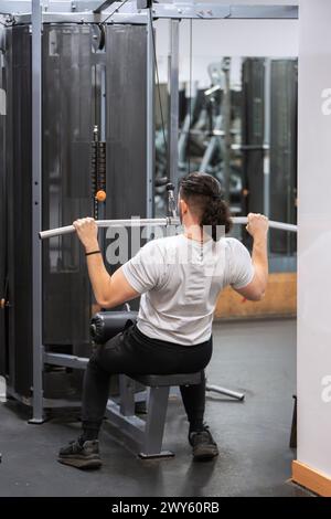 Atleta che fa esercizio di lat pulldown su una macchina presso un centro fitness. Foto Stock