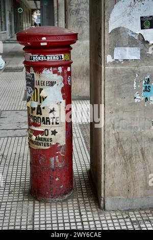 Cassetta per posta rossa vintage coperta da poster Foto Stock