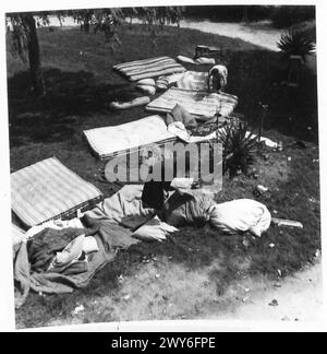 Una FAMIGLIA FRANCESE TORNA AL LORO VILLAGGIO DISTRUTTO DALLE CONCHIGLIE - Madame le Du e Mari-Anne sistemano i letti che sono stati messi in giardino per la messa in onda. , British Army, 21st Army Group Foto Stock