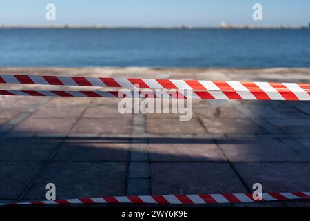 la corda a strisce rosse e bianche si trova a terra. La corda è su una spiaggia vicino all'acqua. Foto Stock