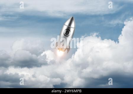 Lancio di un razzo d'argento con un cartello bitcoin sullo sfondo del cielo. Concetto di investimento minimo. Foto Stock