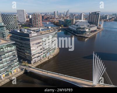 Foto dei droni in basso sul Manchester Ship Canal con il Media City Footbridge e BBC Studios in primo piano con MediaCityUK e Salford Quays Foto Stock