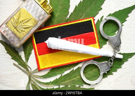 Joint und Deutschland-Fahne auf Cannabis-Blatt mit Handschellen, Cannabis-Legalisierung *** bandiera congiunta e Germania su foglia di cannabis con manette, legalizzazione della cannabis Foto Stock