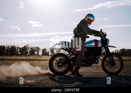 Un motociclista maschio con il casco, che cavalca per strada Foto Stock