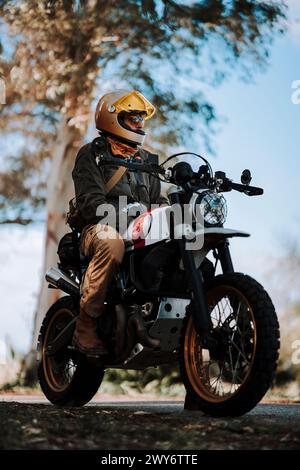 Uomo in moto con casco giallo e giacca nera Foto Stock