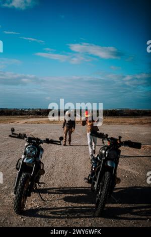 Due uomini che camminano in bicicletta sul marciapiede accanto a una strada Foto Stock