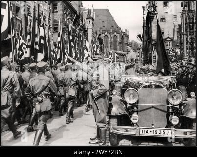 ADOLF HITLER Vintage Nurnberg Norimberga Rally 1935, Germania - SA Sturmabteilung milizia politica truppe del partito nazista, marciano oltre Adolf Hitler durante una parata NSDAP in città. Nel 1930 Adolf Hitler indossa una fascia di svastica in parata militare, in piedi in auto Mercedes libera dà il saluto a Heil Hitler per passare le truppe Sturmabteilung in marcia, con le sue guardie Waffen SS in piedi dietro Norimberga Norimberga Germania Foto Stock