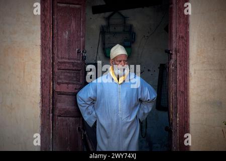 Uomo in felpa con cappuccio in piedi davanti alla porta, che guarda di nuovo alla telecamera Foto Stock