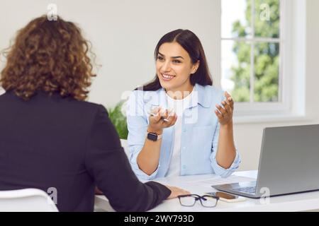 Uomini d'affari al lavoro in ufficio. Due datori di lavoro seduti alla scrivania sul posto di lavoro e che parlano. Foto Stock