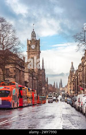 Autobus turistici parcheggiati lungo Princes Street a Edimburgo, Scozia, con la torre dell'orologio del Balmoral Hotel visibile Foto Stock