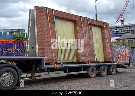 Pareti prefabbricate in cemento e mattoni rossi su un rimorchio che arriva in un cantiere di Edimburgo, Scozia, Regno Unito. Foto Stock