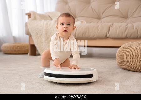 Bambino piccolo con aspirapolvere robot su moquette a casa Foto Stock